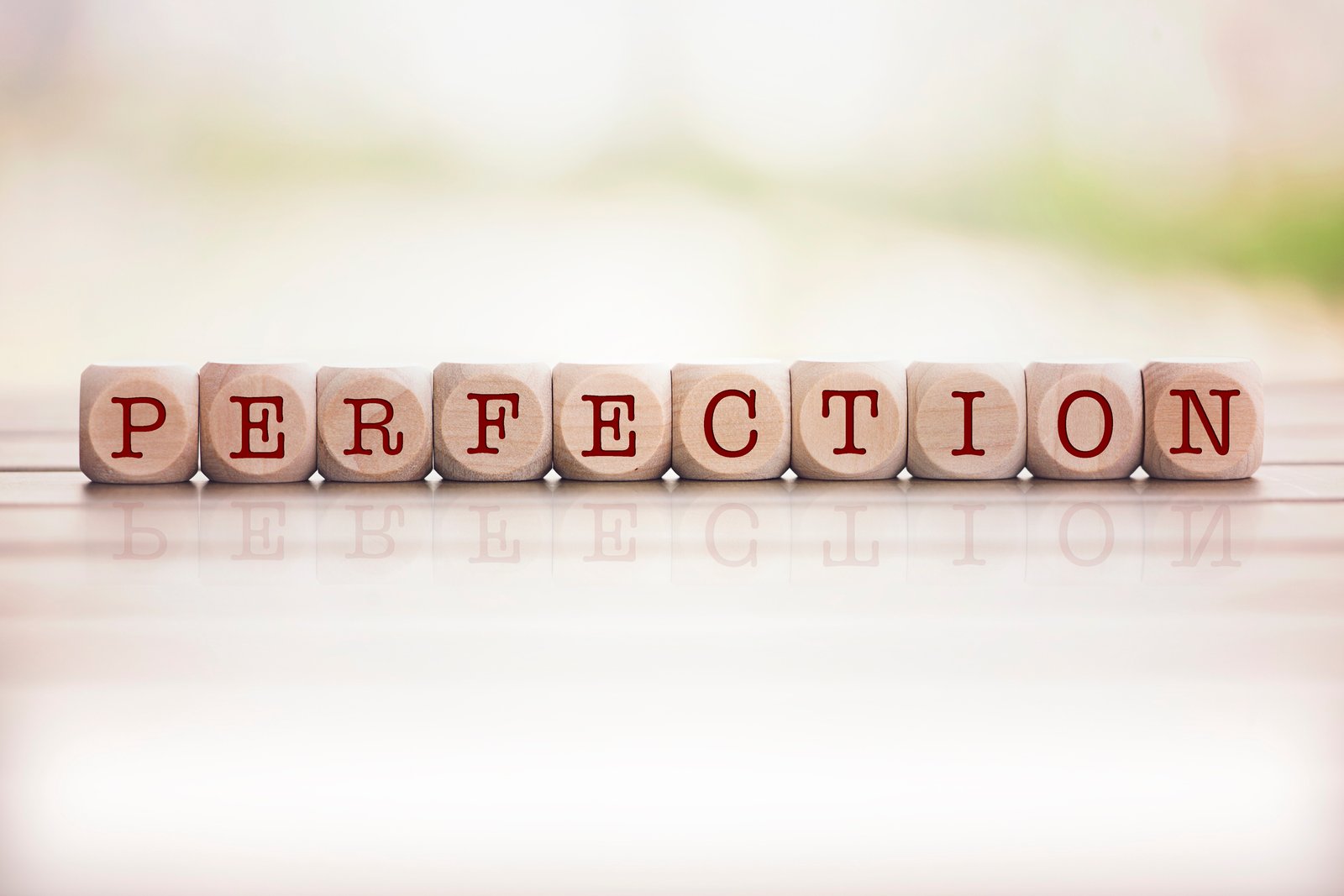 Perfection word written on cube wooden blocks. Defocused background.